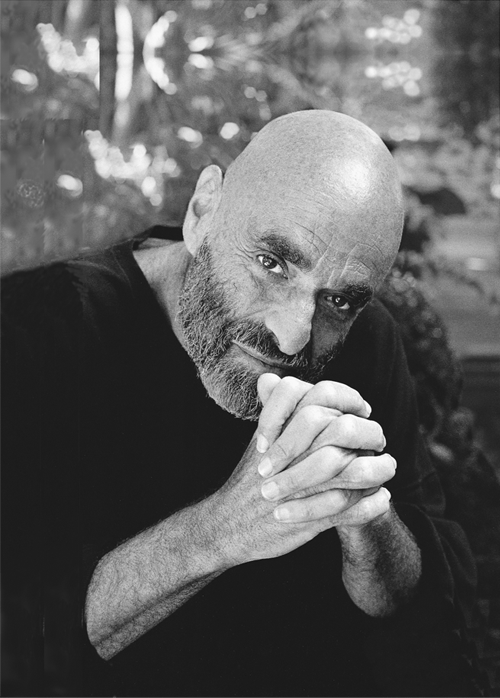 Black and white photo of Shel Silverstein clasping his hands and leaning forward. Photo by Larry Moyer