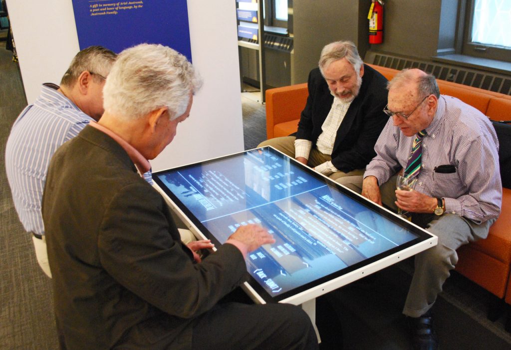 4 older men play a word game together on a touch table at the Word Play exhibit at the American Writers Museum in Chicago, IL