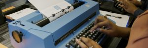 A visitor typing on a large blue IBM typewriter at the American Writers Museum in Chicago, IL