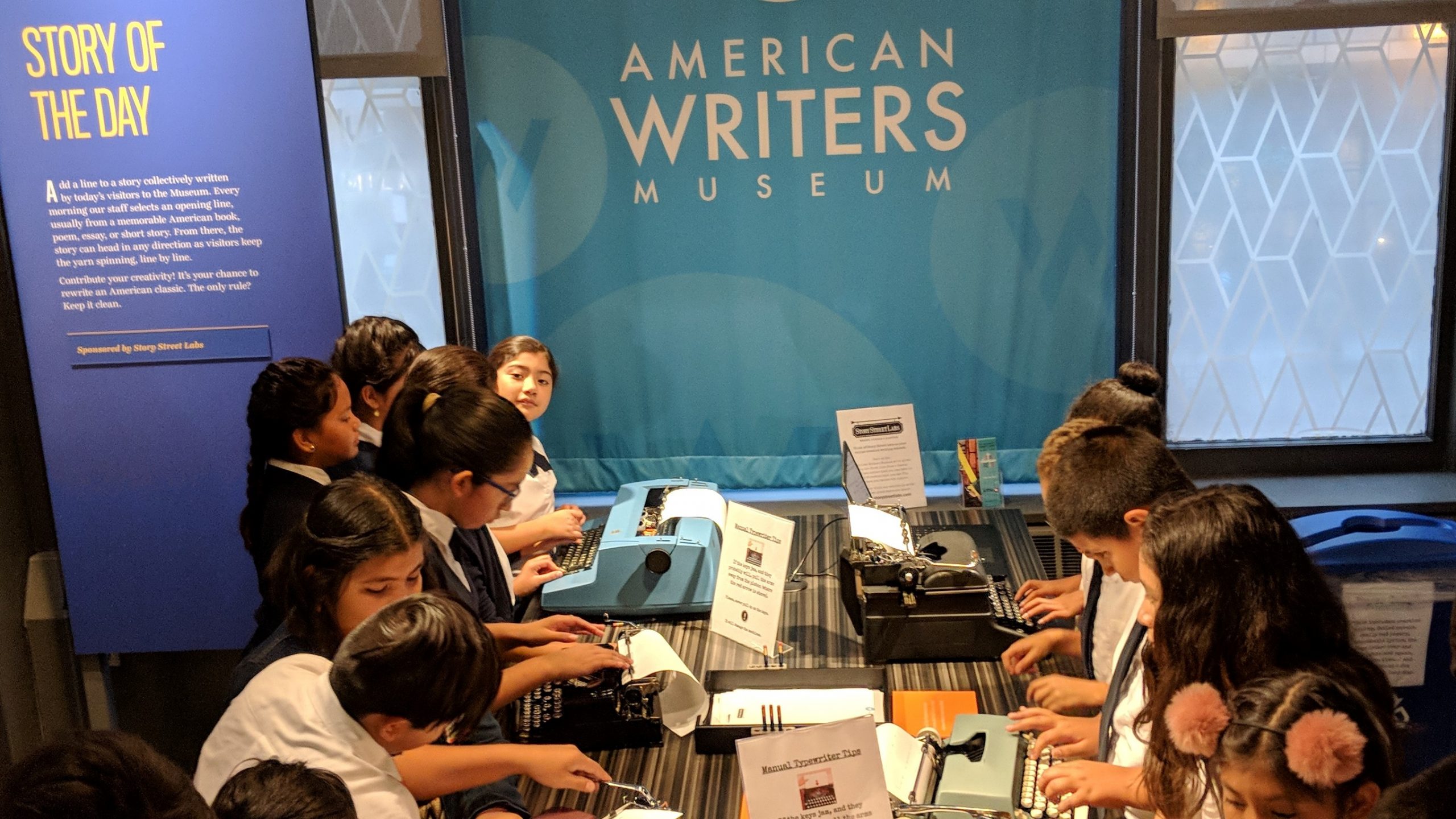 A classroom of students typing at the typewriters in the Story of the Day exhibit