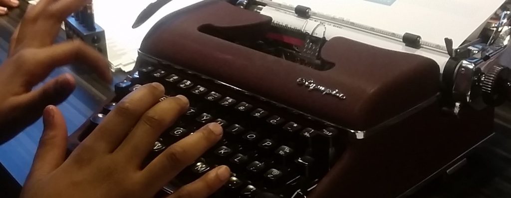 girl's hands typing on a typewriter