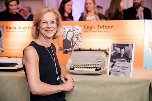 Christie Hefner posing with Hugh Hefner's typewriter
