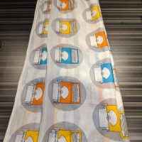A white scarf with a design yellow, orange, and blue typewriters in grey circles. Thin, somewhat sheer material.