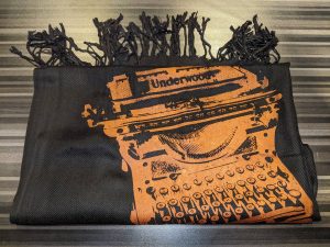 A black scarf with an orange silkscreen design of an Underwood typewriter on it.