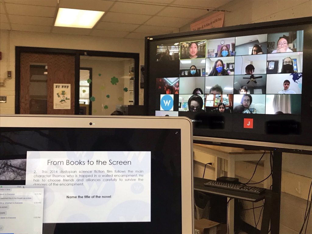 A virtual American Writers Museum field trip. A computer screen in the foreground reads "From Books to the Screen," and a TV screen in the background shows a classroom meeting on Zoom.