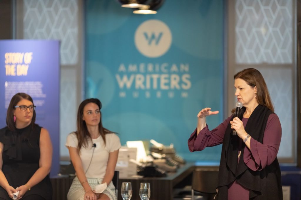 A woman with a microphone presenting at the American Writers Museum