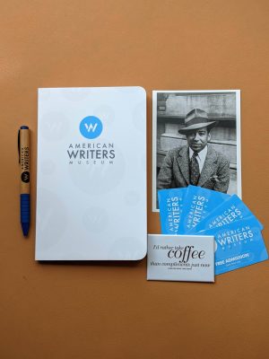 An American Writers Museum branded notebook and pen next to a postcard, a magnet, and 4 passes to visit the American Writers Museum