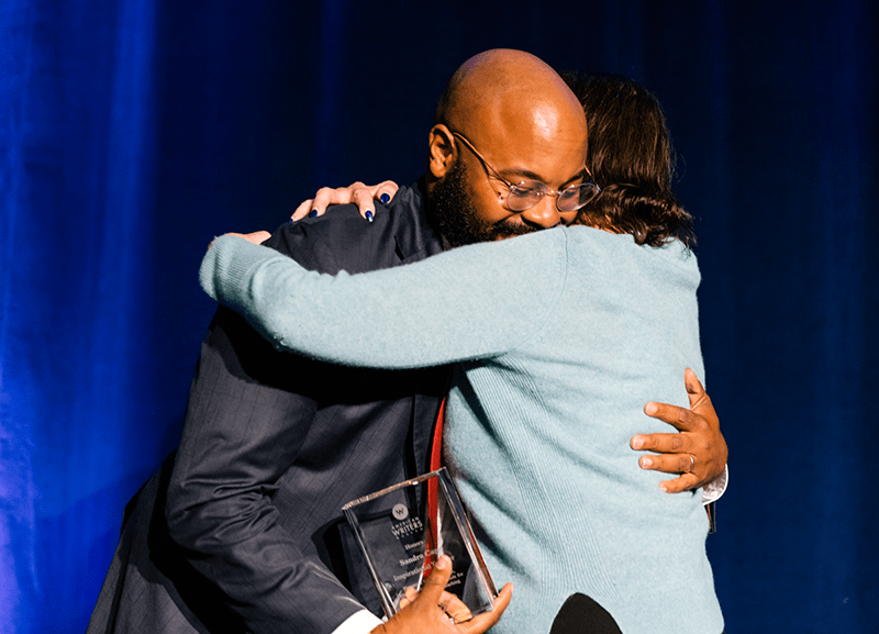 Nate Marshall hugs his former teacher Sandra Cap, recipient of the Inspiring Teacher Award from the American Writers Museum