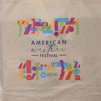 An off-white canvas tote bag with a rainbow colored punctuation design surrounding the words 