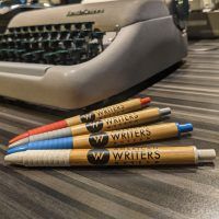 Four American Writers Museum branded bamboo pens in red, grey, blue, and off-white.